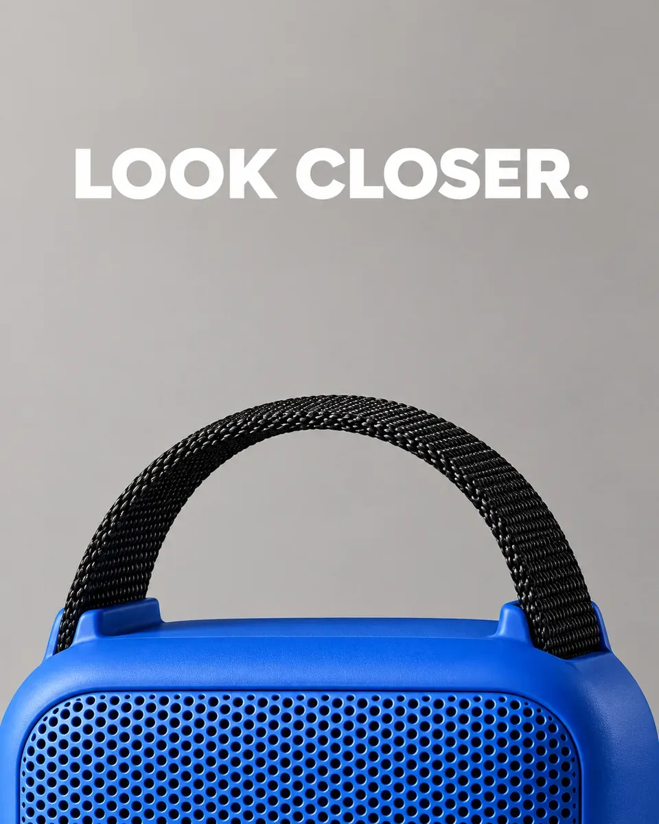 A close-up shows the blue speaker’s front grille, rounded housing, and black webbing handle A close-up shows the blue speaker’s front grille, rounded housing, and black webbing handle